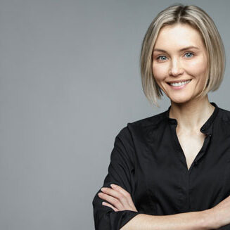 Beautiful middle-aged woman on a gray background in a black blouse smiling.