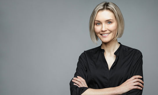 Beautiful middle-aged woman on a gray background in a black blouse smiling.